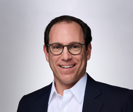 headshot of man with glasses smiling