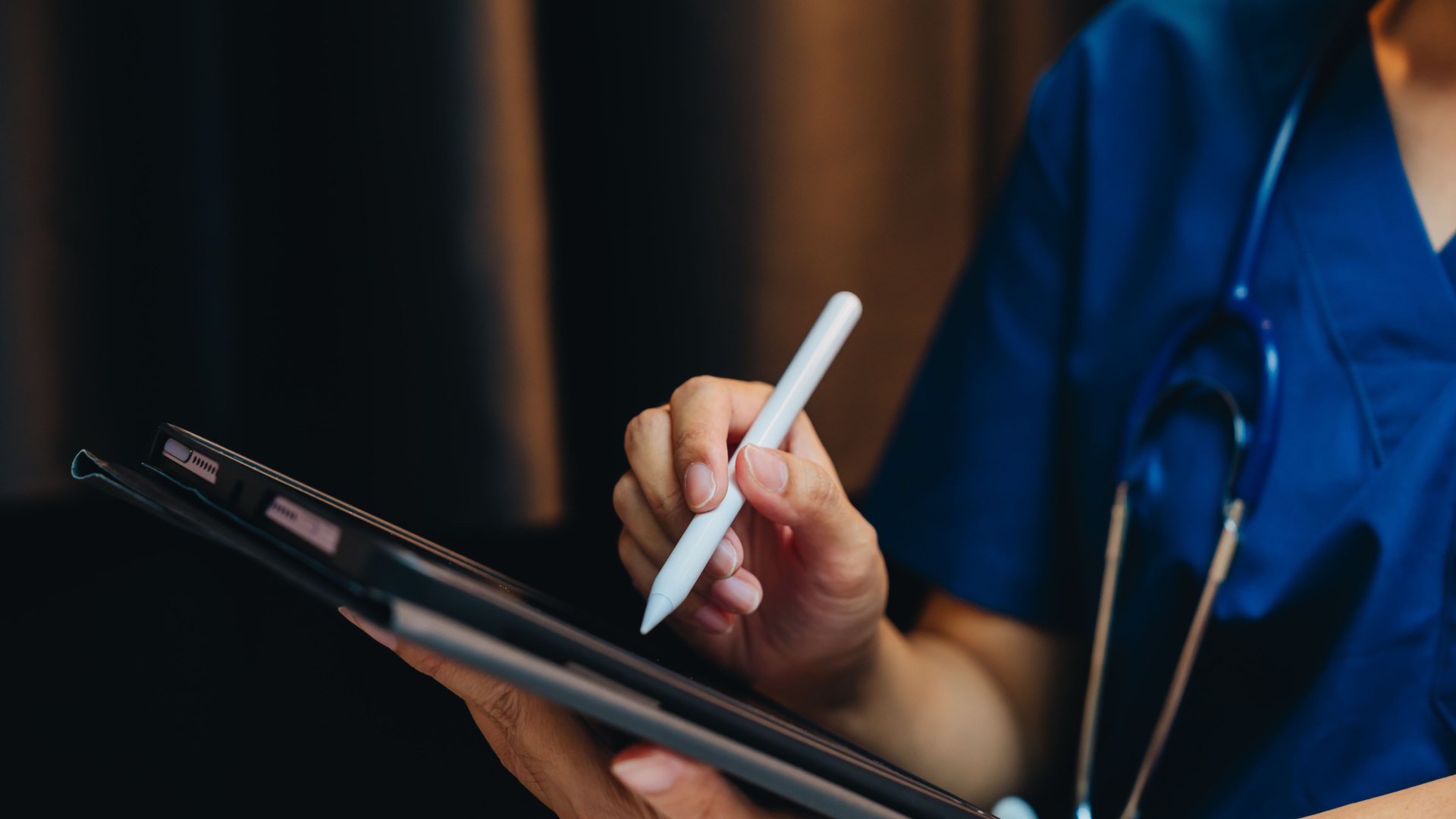 closeup of a doctor in blue scrubs using a tablet