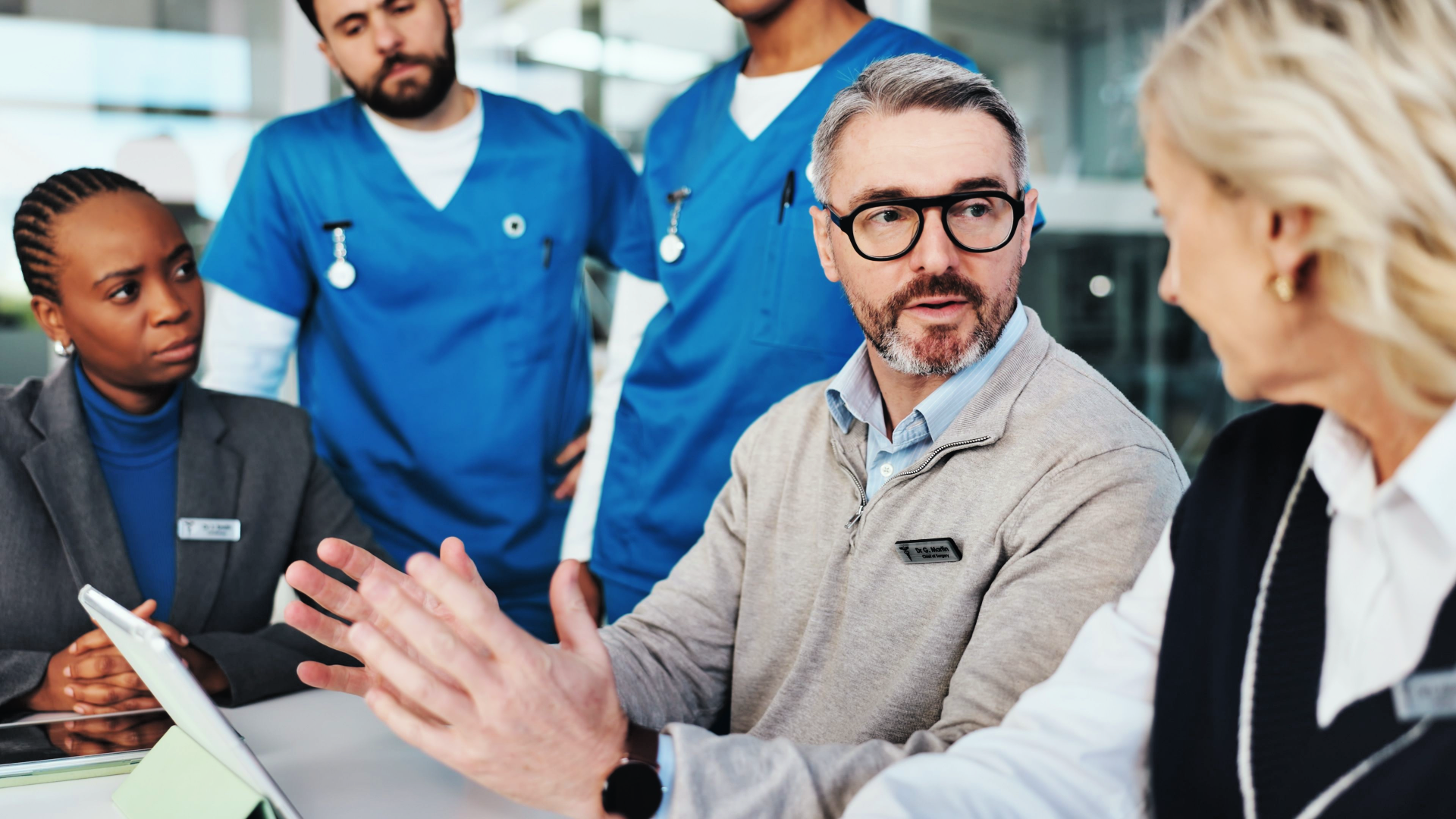a doctor and team of medical professionals talking around a table
